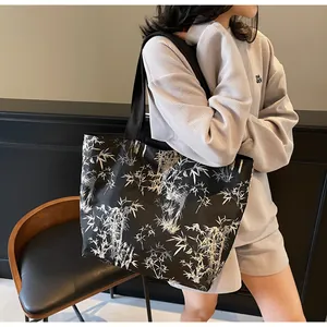 Close-up of a large black tote bag featuring a white bamboo forest print and nylon texture