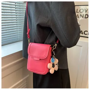 Detailed side view of rose pink mini crossbody phone bag with floral charm and slim strap