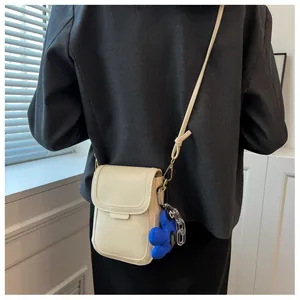 Rear view of a model wearing the cream mini crossbody bag with a blue floral charm