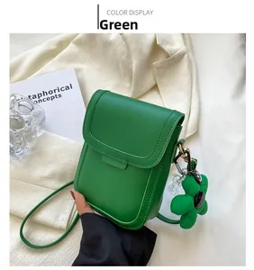 Detail of green leather mobile phone crossbody bag with decorative flower charm