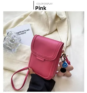 Detailed view of pink mini crossbody bag with a cute blue smiley flower charm