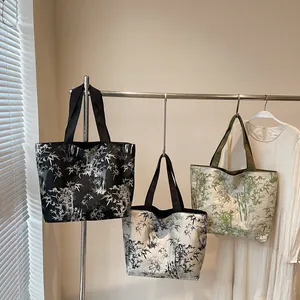 Three large capacity tote bags with bamboo print hanging on a metal rack in soft light