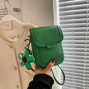 Minimalist green crossbody bag with floral pendant and stitching detail for women