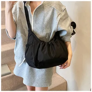 Detail van zwarte crossbodytas met verstelbaar trekkoord en een brede schouderband