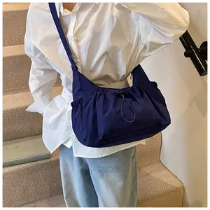 Detailweergave van de donkerblauwe nylon schoudertas met trekkoord gedragen door een model