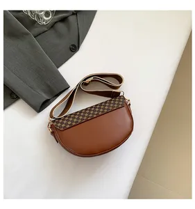 Close-up of a vintage brown saddle bag featuring geometric texture and a wide woven strap