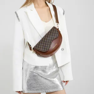 Brown vintage saddle bag with geometric patterns and wide strap on white suit