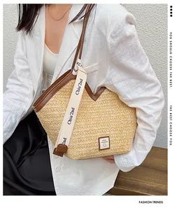 Detail of a beige woven tote bag with brown leather trim carried by a model in a suit