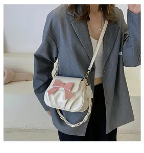 Gros plan du sac plissé crème avec un nœud rose et une boucle en métal doré