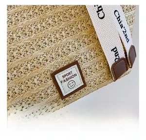 Detail showing woven texture and Sport Fashion logo on a beige straw tote bag