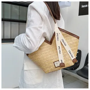 Close-up of woven straw tote bag with brown leather trim and branded canvas straps