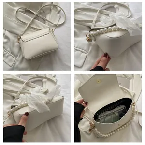 Detail of crossbody bag featuring large pearl handle and soft chiffon bow accent