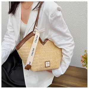 Detail of woven straw tote bag with brown leather trim and stylish logo webbing strap