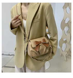 Détail d'un sac bandoulière beige plissé avec nœud marron et bandoulière en cuir