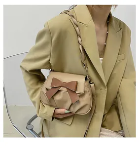 Détail du sac bandoulière beige plissé avec nœud marron et bandoulière tressée