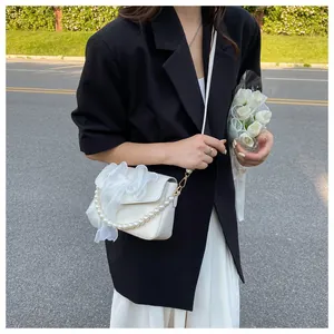 Detail of white mini crossbody bag featuring a large tulle bow and elegant pearl handle