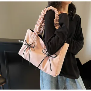Detail of pink nylon tote bag with pleated handle and black decorative bow accents