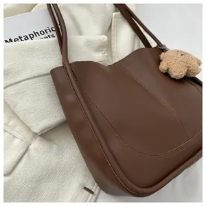 Close-up of brown PU tote bag featuring U-shaped stitching and a cute bear keychain