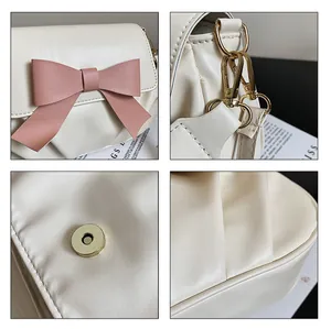 Détails d'un sac bandoulière en cuir PU crème avec nœud rose et côtés plissés
