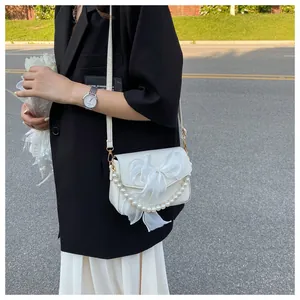 Detail of cream crossbody bag with large organza bow and white pearl chain strap