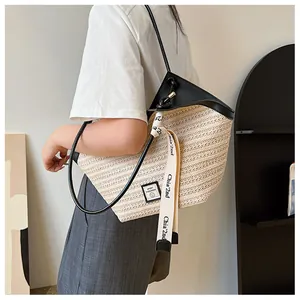 Detail of woven straw tote bag featuring contrast leather trim and chic brand logo patch