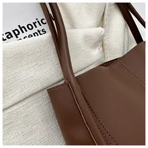 Detail shot of the reinforced stitching and leather texture on a brown tote bag handle