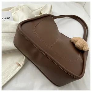 Detail view of large brown PU leather tote bag with stitch decor and cute bear charm
