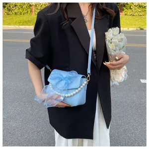 Detail of light blue crossbody bag with mesh bow decoration and pearl chain strap