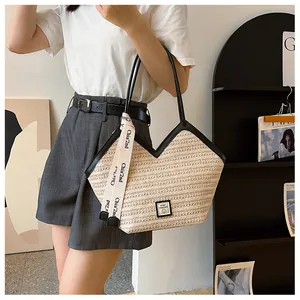 Detail of woven straw tote bag with V-shaped opening and black leather long handles