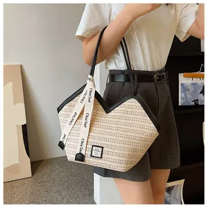 Detail of woven straw tote bag featuring contrast black trim and v-shaped edge design