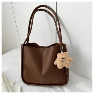 Detail of dark brown leather tote bag with contrast stitching and plush star pendant
