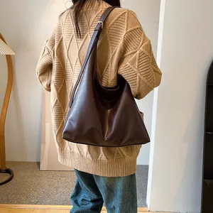 Gros plan du grand sac cabas en cuir marron foncé montrant le drapé et la texture sur modèle