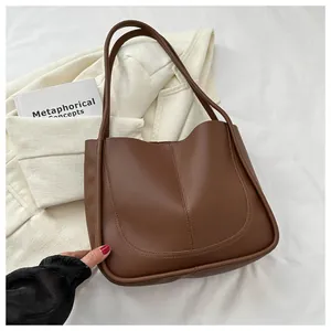 Detailed close-up of dark brown PU leather tote bag with unique U-shaped stitching