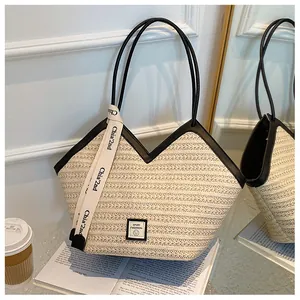 Detail of woven straw tote bag with black trim and SPORT FASHION logo on a desk