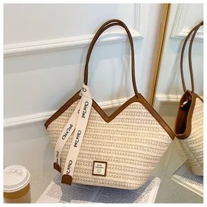 Detail of woven tote bag with V-shaped opening, brown leather trim, and chic ribbon tie