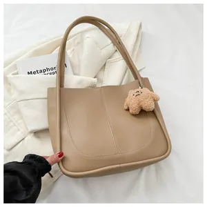 Detail of light brown PU tote bag with U-shaped stitching and cute plush bear charm