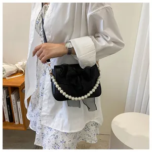 Detail of crossbody bag with sheer organza bow and pearl handle shown on model