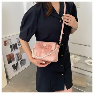 Detail of pink crossbody bag with large chiffon bow and decorative pearl chain