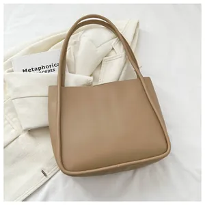 Detail of the high-capacity khaki tote bag with piping on a white blazer background