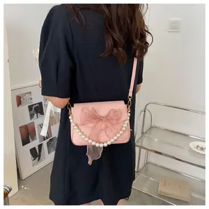 Detail of pink PU crossbody bag featuring a large bow and elegant pearl chain strap