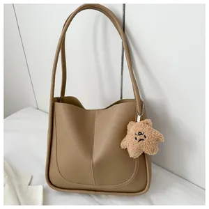Close-up of camel PU leather tote bag with a unique plush star-shaped charm and stitching