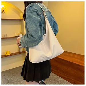 Lifestyle shot of a minimalist cream tote bag worn as a shoulder bag in a cafe
