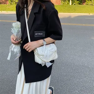Chic white crossbody bag featuring a large tulle bow and pearl chain handle for women