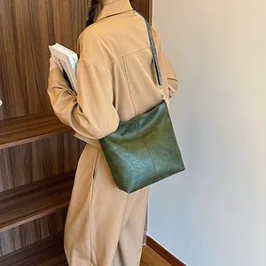 Retro dark green tote bag with ethnic patterned wide strap on a model shoulder