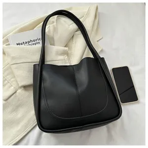 Detailed view of black PU leather tote bag with U-shaped stitching and long shoulder straps