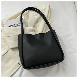 Detail of a large matte black PU leather tote bag with soft rounded edges and long straps