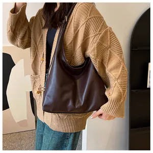 Deep brown matte leather hobo bag worn by a model in a modern office interior