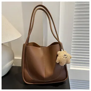 Close-up of brown PU leather tote bag with star plush charm and stitched details