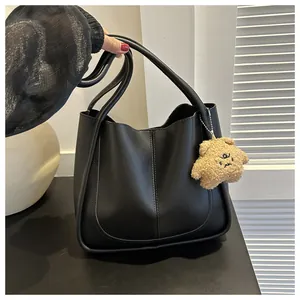 Detail of black PU leather tote bag with a cute plush bear charm and sturdy handles