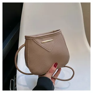 Detail of khaki pebbled leather crossbody bag with triangular flap and gold metal bar
